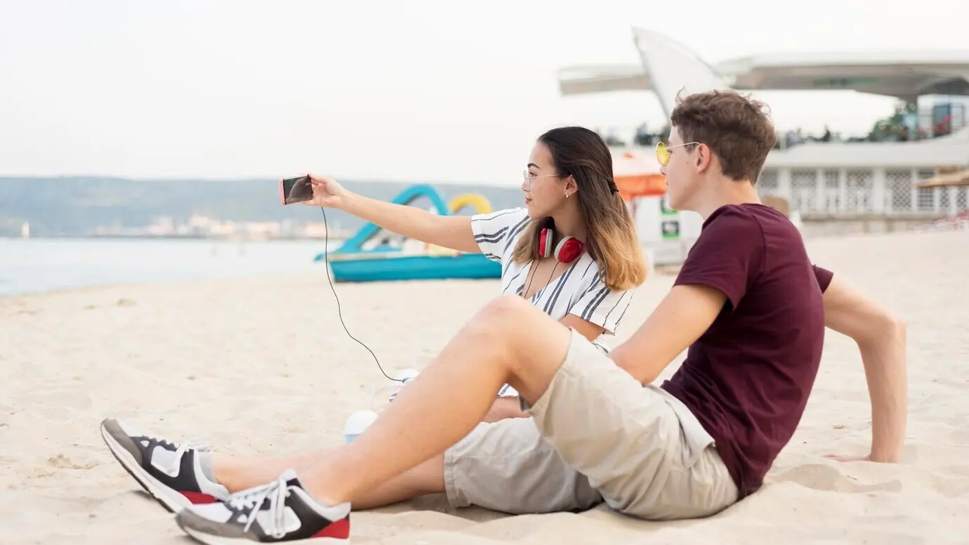 Teenager, die zusammen am Strand ein Selfie machen.